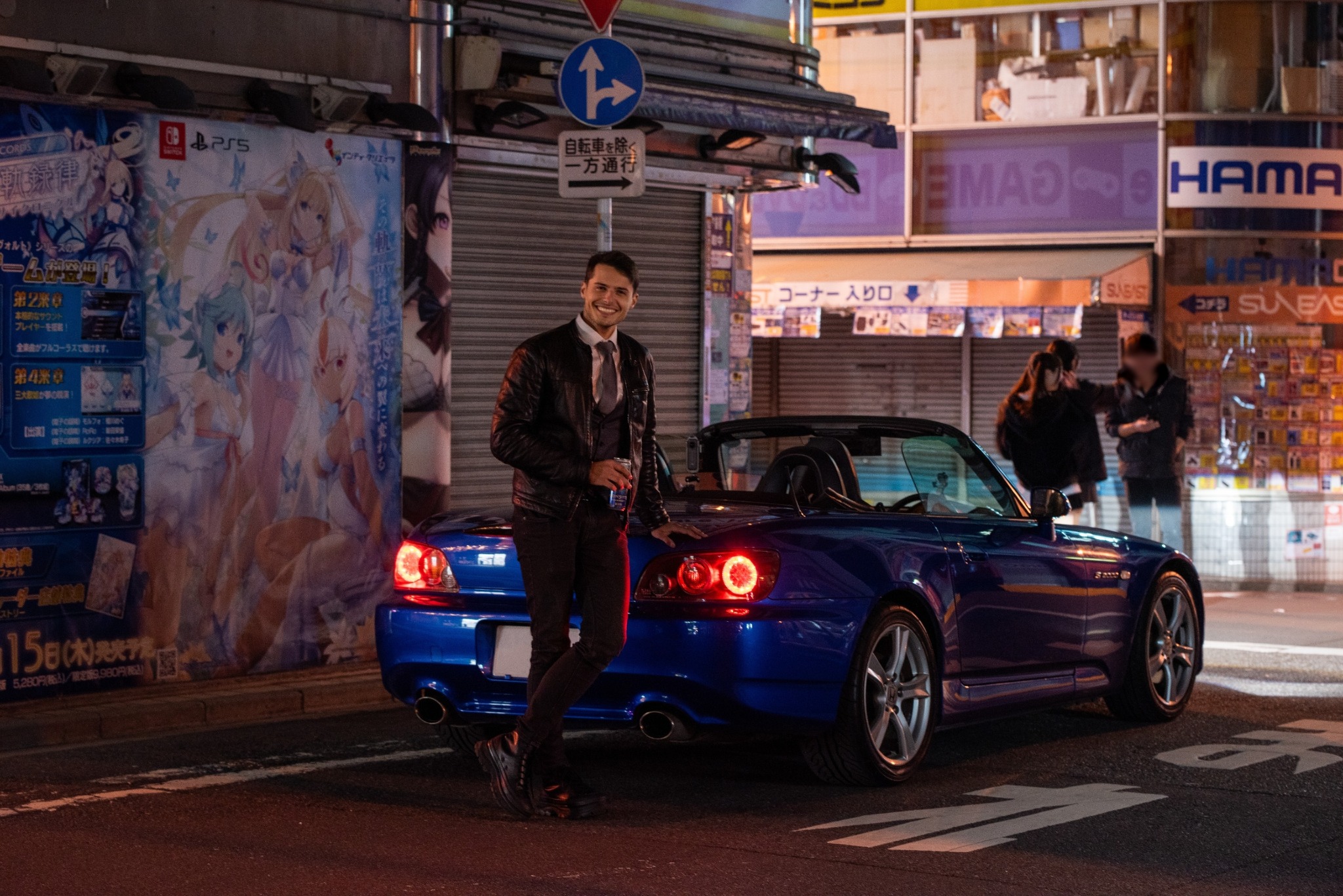 Mark Filipkov standing beside a blue Honda S2000 in Akihabara at night
